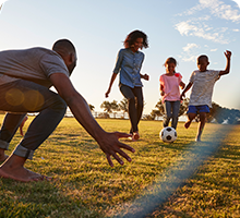 A family playing a game of football in the park